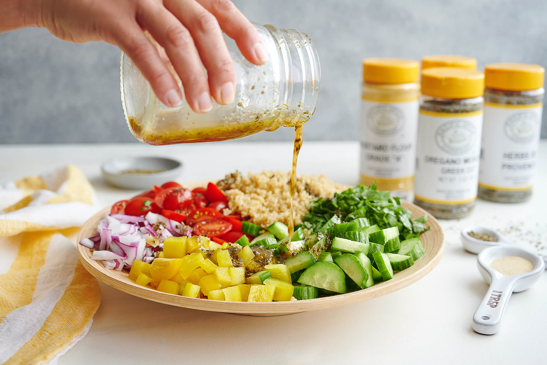 image of bowl with quinoa salad and pacific spice company spices in the background